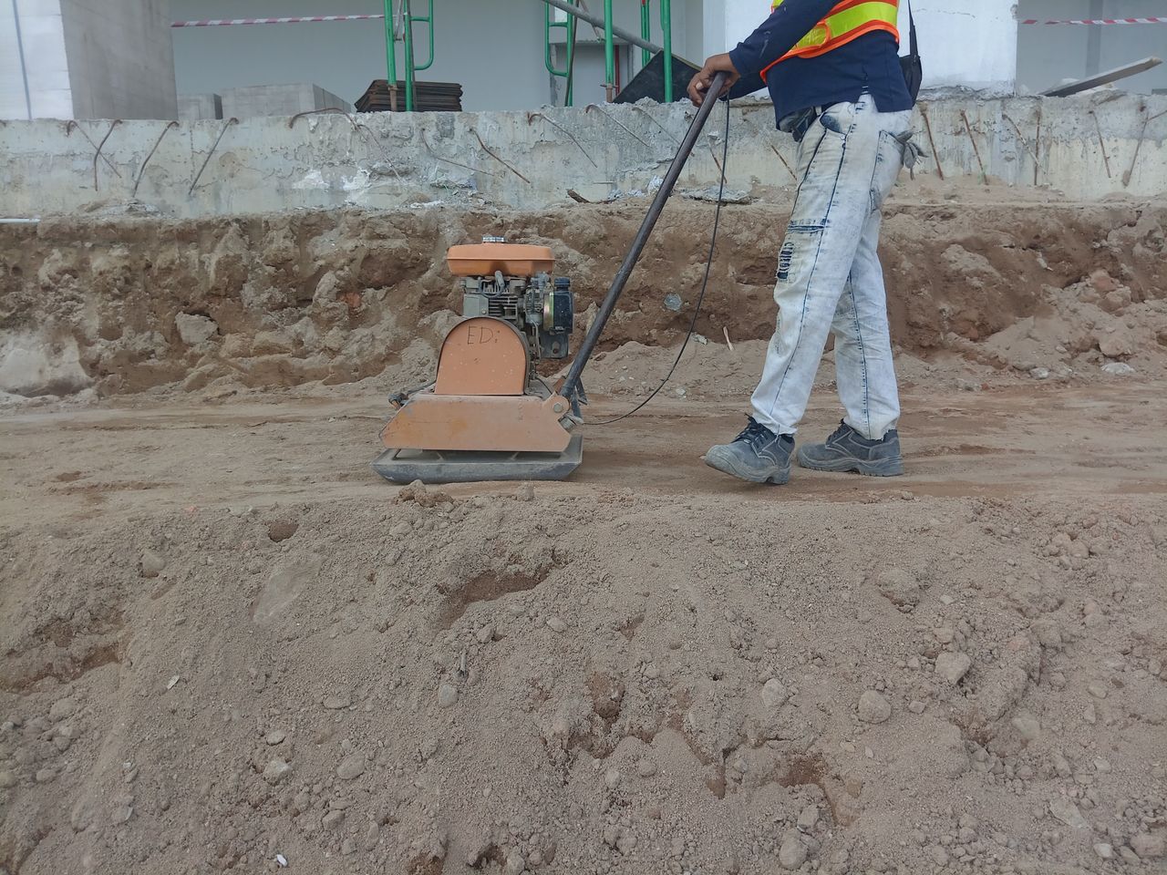 Operator care compactează stratul de bază înainte de turnarea betonului