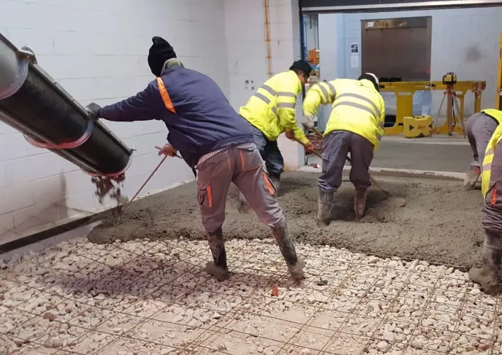 Echipă care toarnă și nivelează betonul peste stratul pregătit